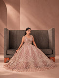 Model seated on a sofa in a blush sequin gown with a full flared skirt